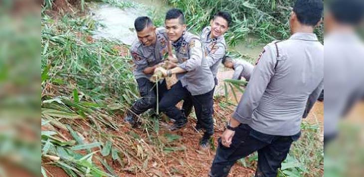 Para personil Polres Bandung berjibaku mengangkat bambu di Sungai Cibintinu.

