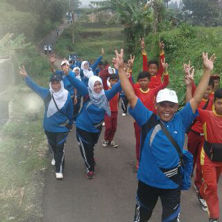 Para guru dan siswa mengangkat tangan saat mengikuti jalan sehat HUT PGRI tingkat Kec Cimaung, Kamis (24/11).