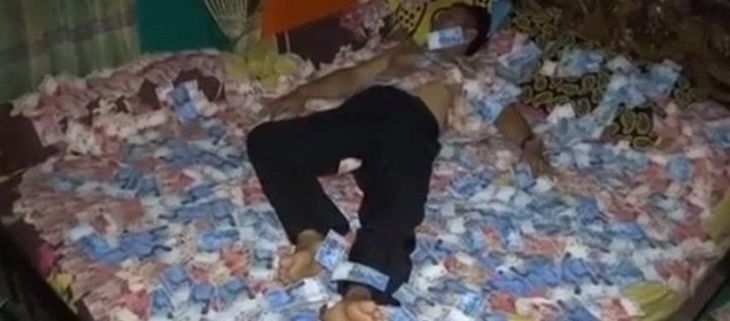 Salah satu potongan video seorang pria diduga kades pamer tidur beralas uang (Facebook/Radar Mojokerto)