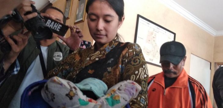 Seorang polwan saat membawa bayi korban penculikan. (Foto: detikcom)