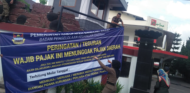 Sejumlah anggota Satpol PP KBB saat memasang spanduk spanduk bertuliskan 'Wajib Pajak Ini Menunggak Pajak Daerah' disalah satu lokasi di KBB.