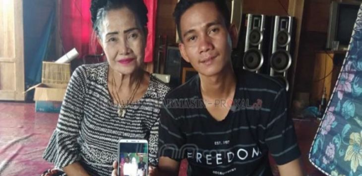 Patimah (56) dan Riswan (22) menunjukkan foto pernikahannya.