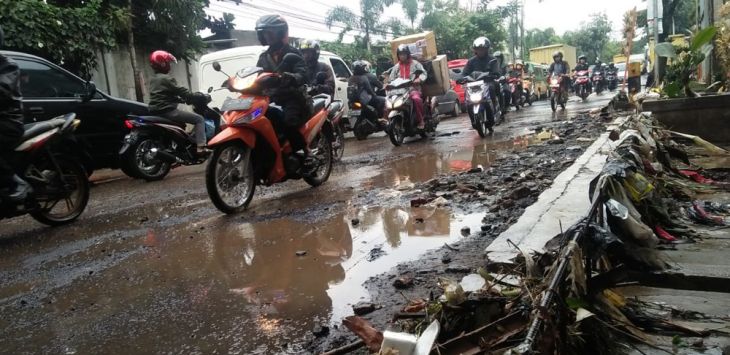 RUSAK:  Pengendara sepeda motor melintas di Jalan Mahar Martanegara, Kota Cimahi. Senin, (25/02/2019). Aspal yang mengelupas di sepanjang jalan tersebut hingga saat ini belum diperbaiki.(foto:Arip Rahman )