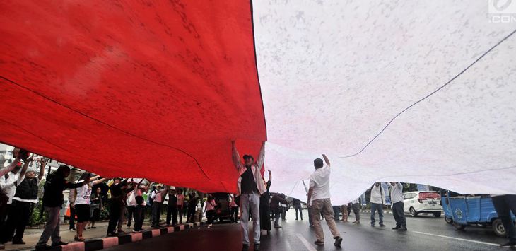 MEMBENTANGKAN: Ratusan warga membentangkan bendera merah putih berukuran raksasa untuk menyemarakan HUT RI. 
( IST )