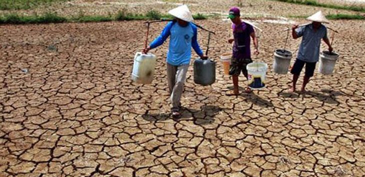 ILUSTRASI : Warga berjalan sambil mengangkut air melintasi sawah yang mengalami kekeringan akibat kemarau panjang. (foto : IST )