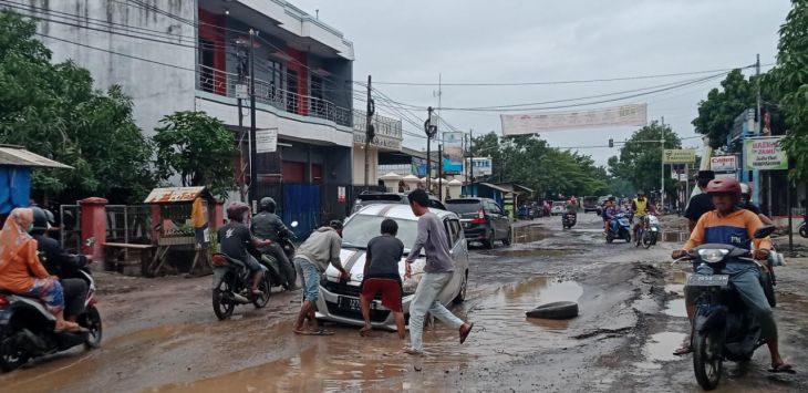 TERJEBAK KUBANGAN : Warga evakusi mobil yang terjebak kubangan di jalan Ion Martasasmita, Pamanukan ,Subang, Minggu, (21/2/2021)(foto : M.ANWAR/RADAR BANDUNG)