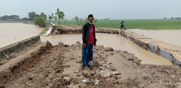 JEBOL LAGI : Seorang Warga menujukkan tanggul di Desa Bongas kembali jebol diterjang arus Sungai Cipunagara setelah dilakukan upaya perbaikan oleh warga bersama TNI dan Relawan pada Senin (22/2/2021). (foto: M.ANWAR/RADAR BANDUNG)