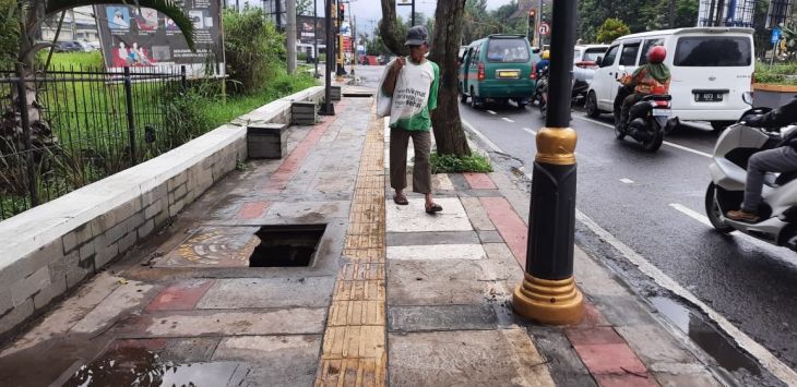 MELINTAS : Seorang warga tengah melintasi lubang bak kontrol trotoar yang tidak memiliki penutup. (Fikriya Zulfah/Radar Bandung)