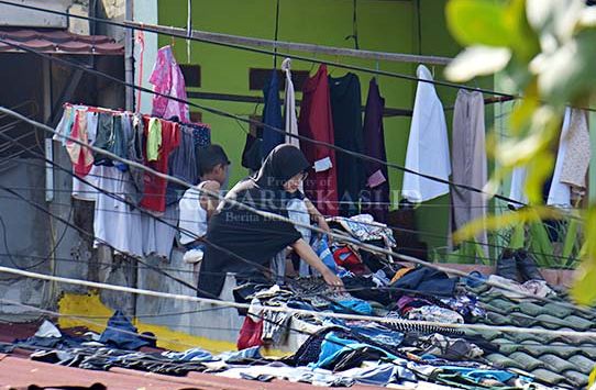 JEMUR PAKAIAN: Warga menjemur pakaian di lantai dua pasca banjir di Perumahan Villa Mutiara Cibitung, Kabupaten Bekasi, Minggu (21/2/2021). (foto: ARIESANT/RADAR BEKASI)