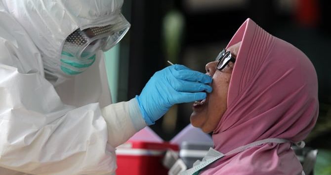 Petugas melakukan pengambilan cairan di tenggorokan dan hidung warga saat Swab test PCR Covid-19. (ist)