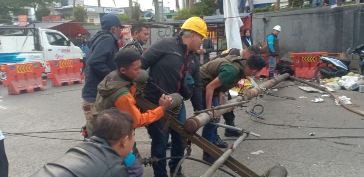 EVAKUASI: Petugas PLN Bersama warga tengah mengangkat tiang yang roboh di Lembang.