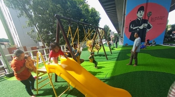 Momen hangat di taman kota, dari anak-anak yang asyik mencoba seluncuran hingga orang tua yang mengawasi sambil berbincang, ruang publik di bawah flyover ini menjadi titik kumpul baru bagi komunitas. Tempat di mana interaksi sosial dan kebahagiaan sederhana terjalin di tengah hiruk pikuk kota. Foto : Taofik Achmad Hidayat/Radar Bandung/Pojok Bandung


